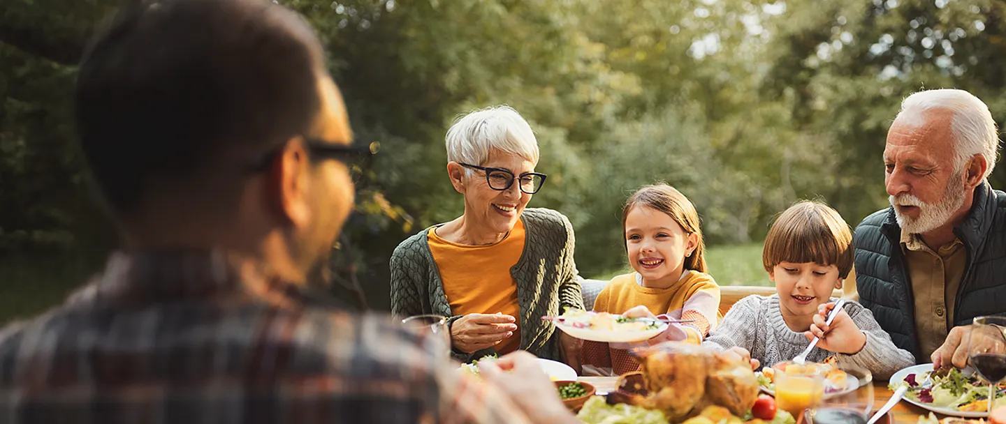 Glückliche Mehrgenerationenfamilie beim Mittagessen in der Natur.
